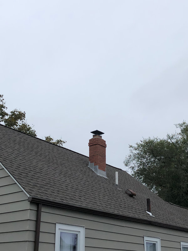 Gray asphalt roofing installed around chimney